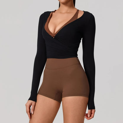 Long sleeve black wrap yoga shirt with V-neckline, styled casually with brown shorts for a chic, sporty look.