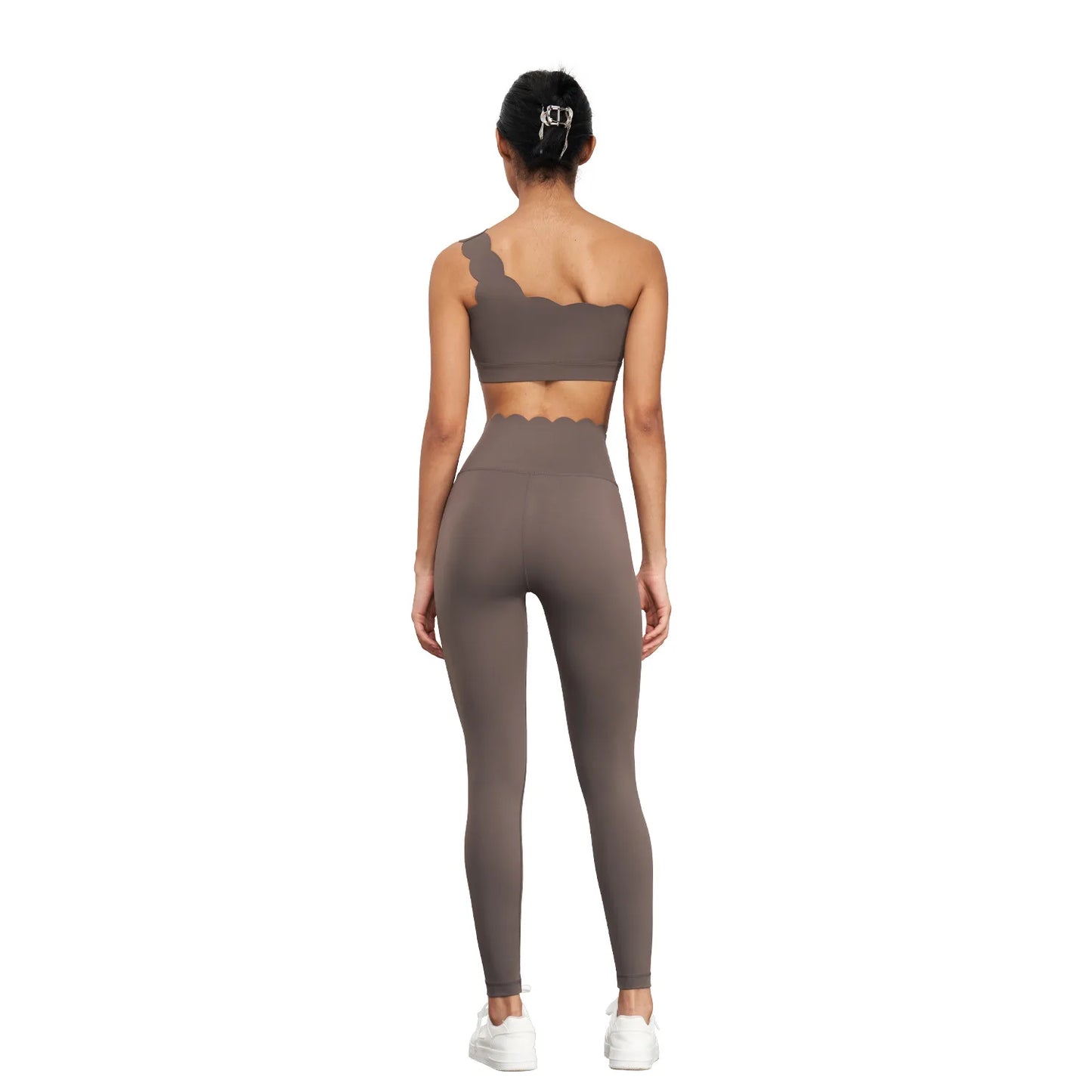 One-shoulder nude yoga bra with scalloped edges, styled with matching high-waisted leggings, showcasing elegance and support.