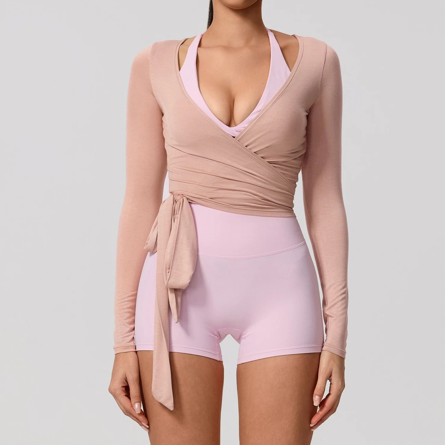 Light pink long sleeve wrap yoga shirt with a flattering V-neckline, perfect for stylish activewear.