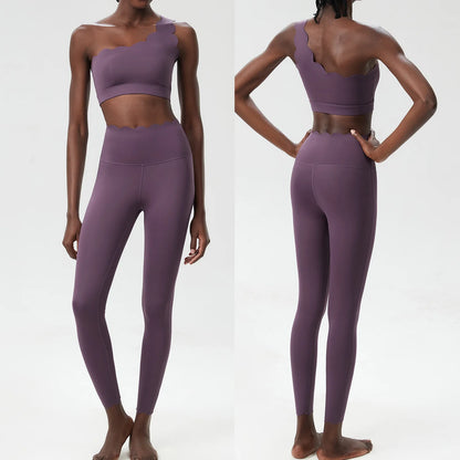 Stylish two-piece fitness yoga set featuring a cropped top with unique shoulder design and high-waisted leggings in muted purple.